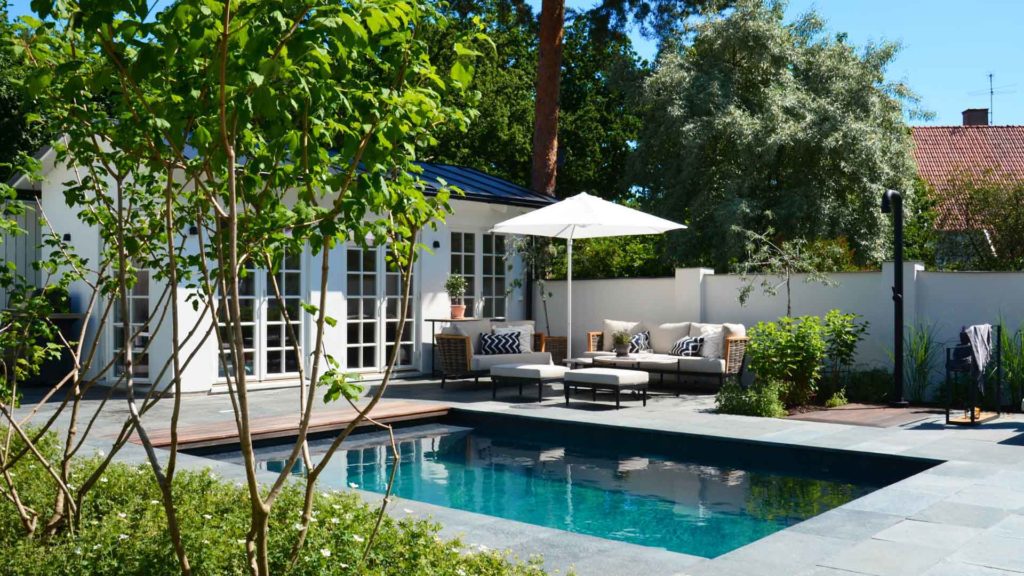 Terrace with pool covered with slate outdoor tiles and a sitting area with parasol.