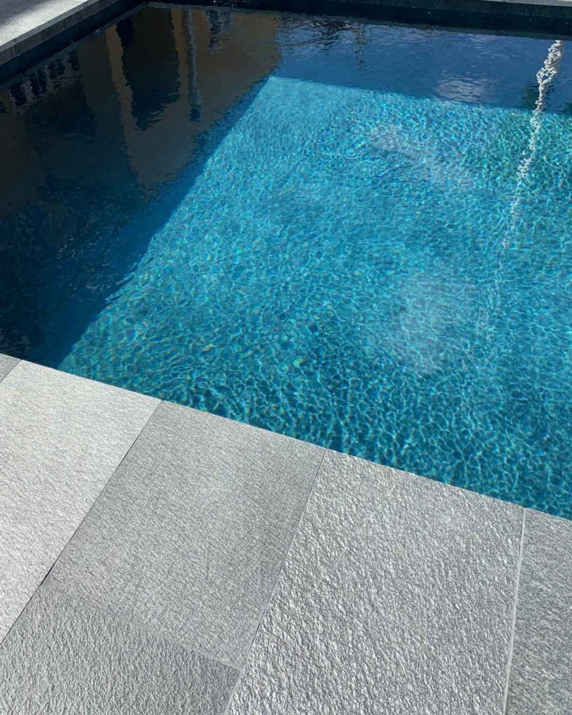 A close-up of a pool in a garden. Slate tiles from Offerdal are surrounding  the pool.