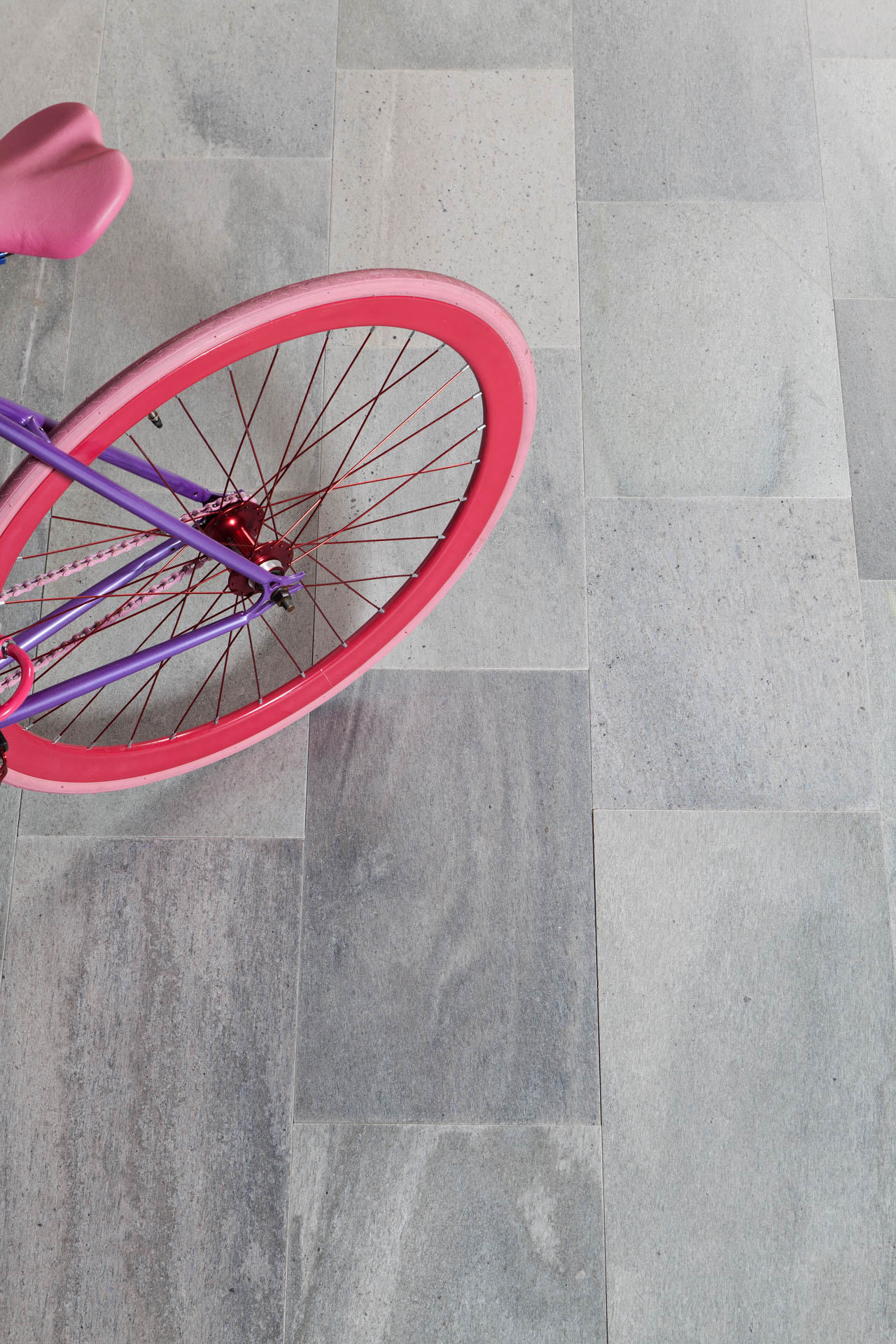 Close up of a slate tile floor with a pink bicycle