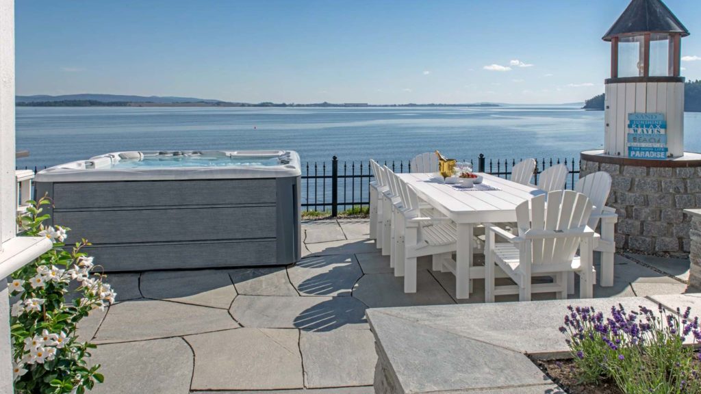 En terrasse med boblebad og spisebord og med lys Oppdal bruddskifer på bakken samt til blomstebed.