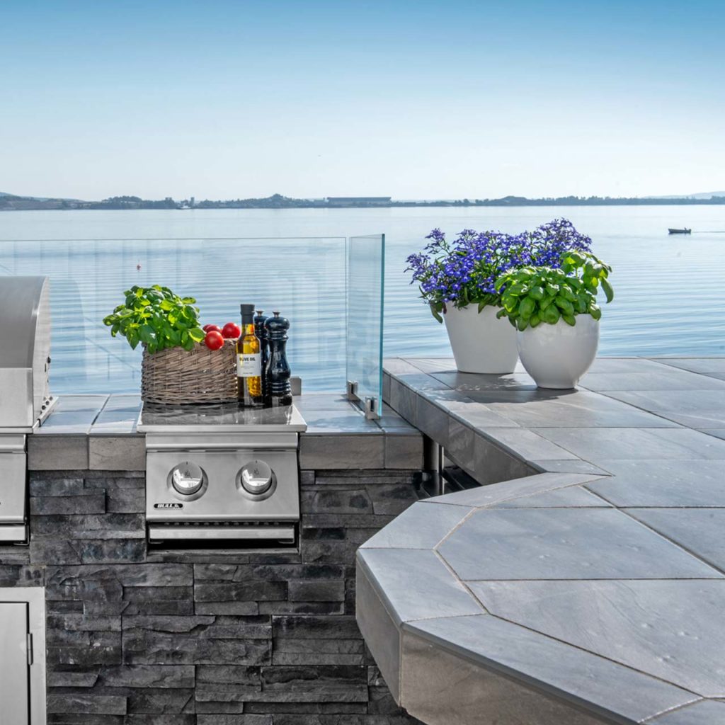 An outdoor kitchen on a terrace facing the sea. The worktop is coated with slate from Oppdal cut into different geometric shapes.