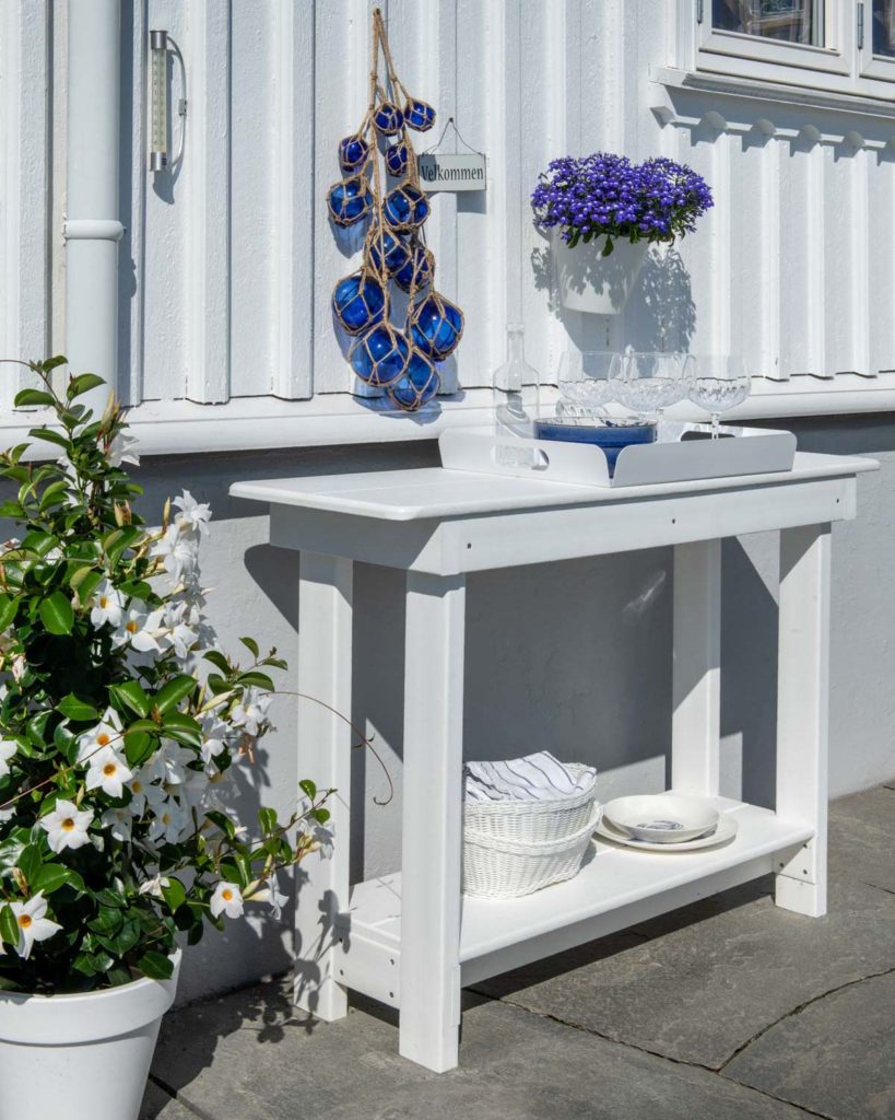Et hvitt trebord med serveringsbrett står på en terrasse med bruddskifer i lys Oppdalskifer.