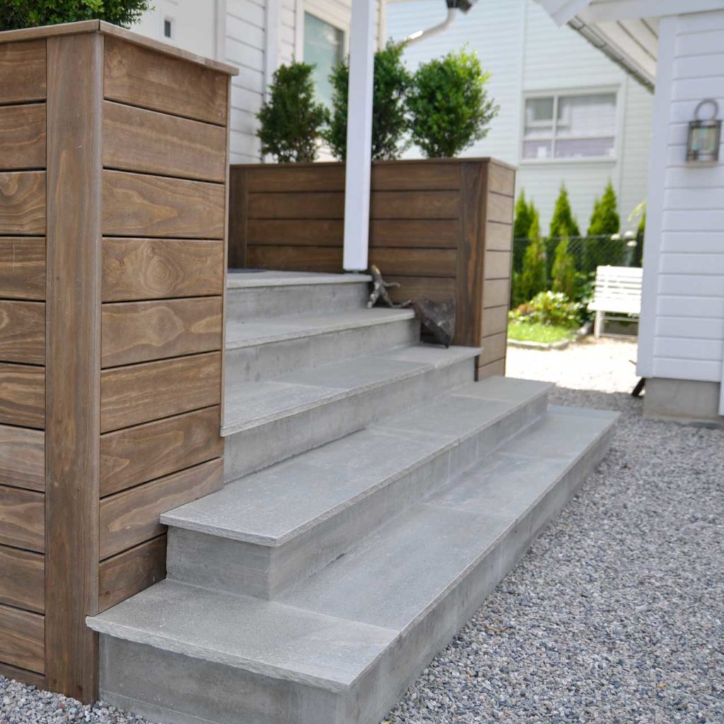 Outdoor natural stone staircase in the entrance area with steps of Oppdal slate with hewn edges. The slate staircase is framed by Kebony wood.