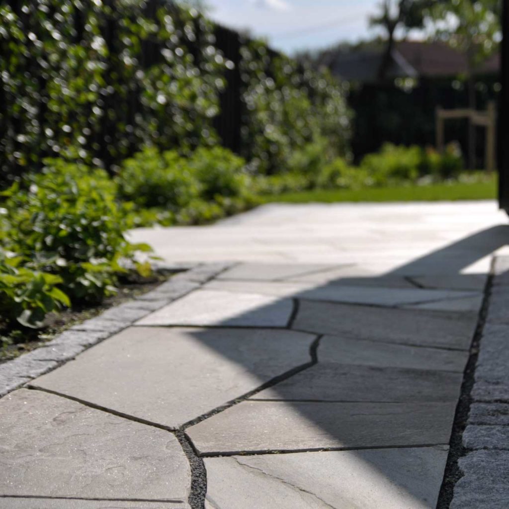 A footpath along a house covered with broken slabs of Oppdal slate with a seamless transition to outdoor tiles in the same type of slate on the terrace.