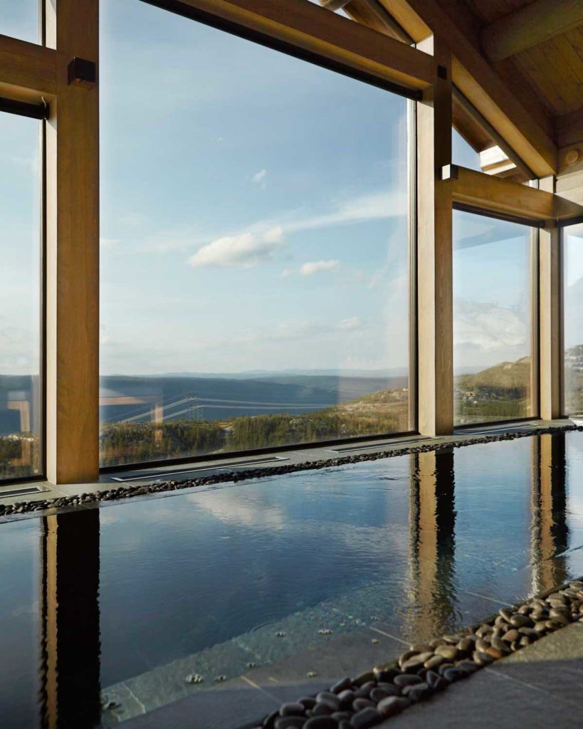 En pool innomhus med skifferplattor av Offerdalsskiffer och med stora fönster som ger panoramautsikt.