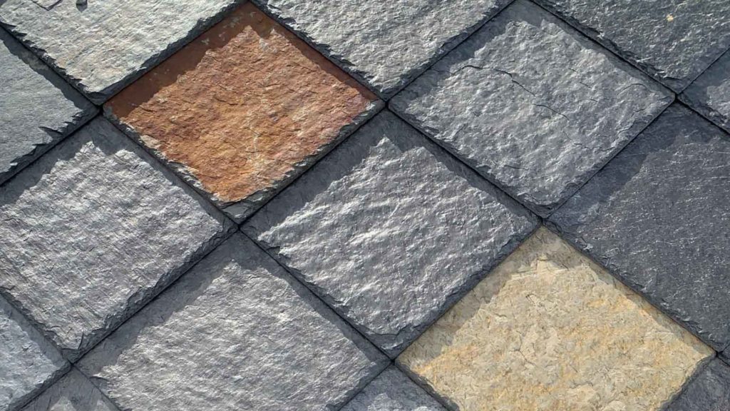 A close-up of black and rusty colored Otta slate roofing tiles slate with a scissored edge.