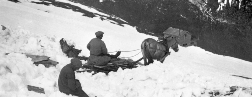 Et bilde fra 1930 tallet av en skiferarbeider som frakter skifer med hest og slede over snødekt fjell.