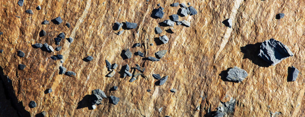Et nærbilde av en brun skifer fra Otta med små steinbiter liggende oppå.