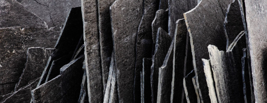 Thin black slabs of slate of Otta Pillarguri that are stacked vertically.