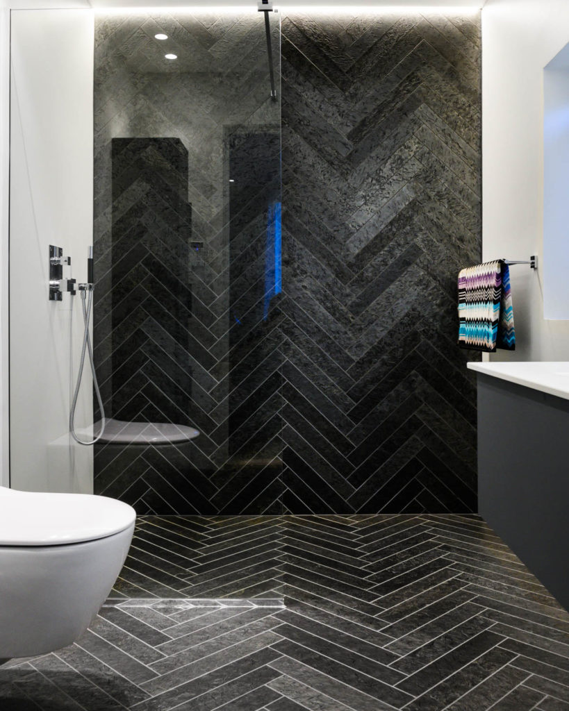 A modern bathroom with black Otta slate tile on the wall and floor in herringbone pattern