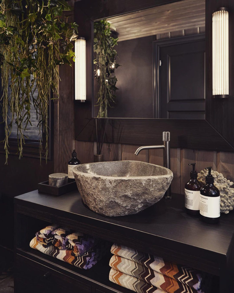 Cozy bathroom in a cabin with slate floors, wooden walls, dark decor and a nice stone sink.