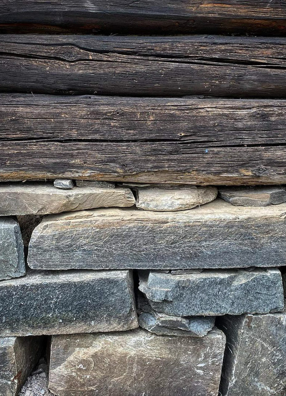 En grunnmur i stein fra Offerdal med en bygningskropp av gammelt tømmer