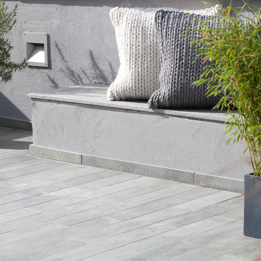A terrace with a cast bench in concrete and narrow slate tiles as a terrace deck.