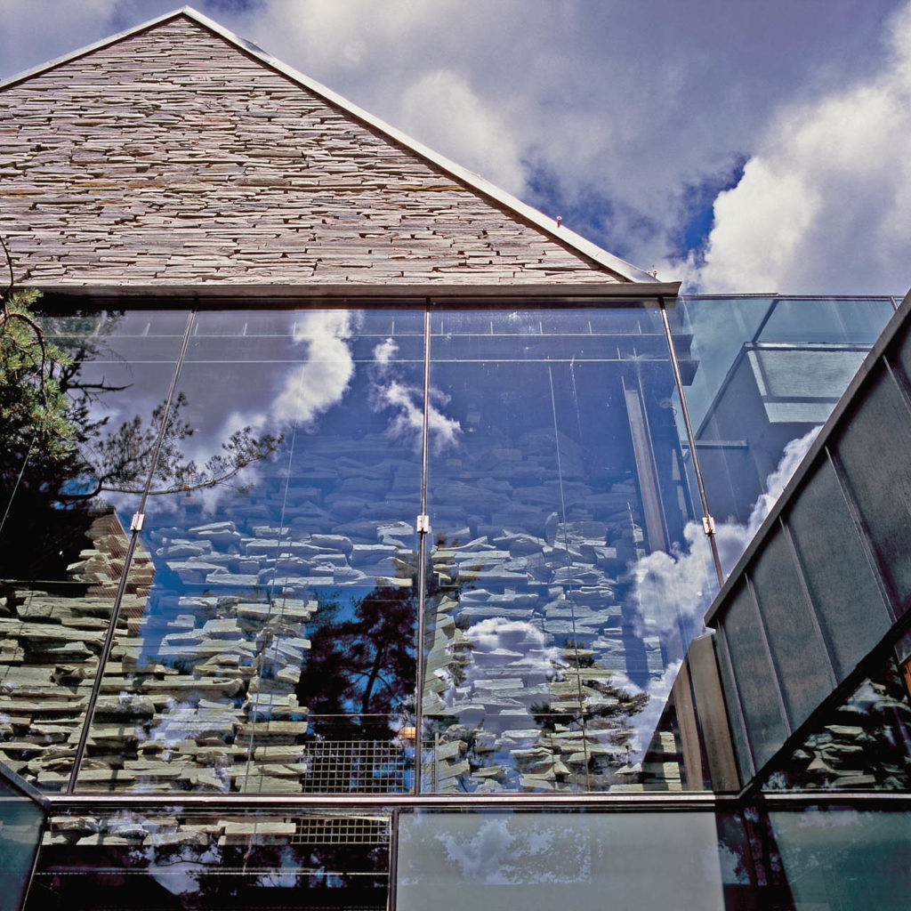 En modern byggnad med skiffertegel monterad som torrmur tillsammans med stora glasytor.