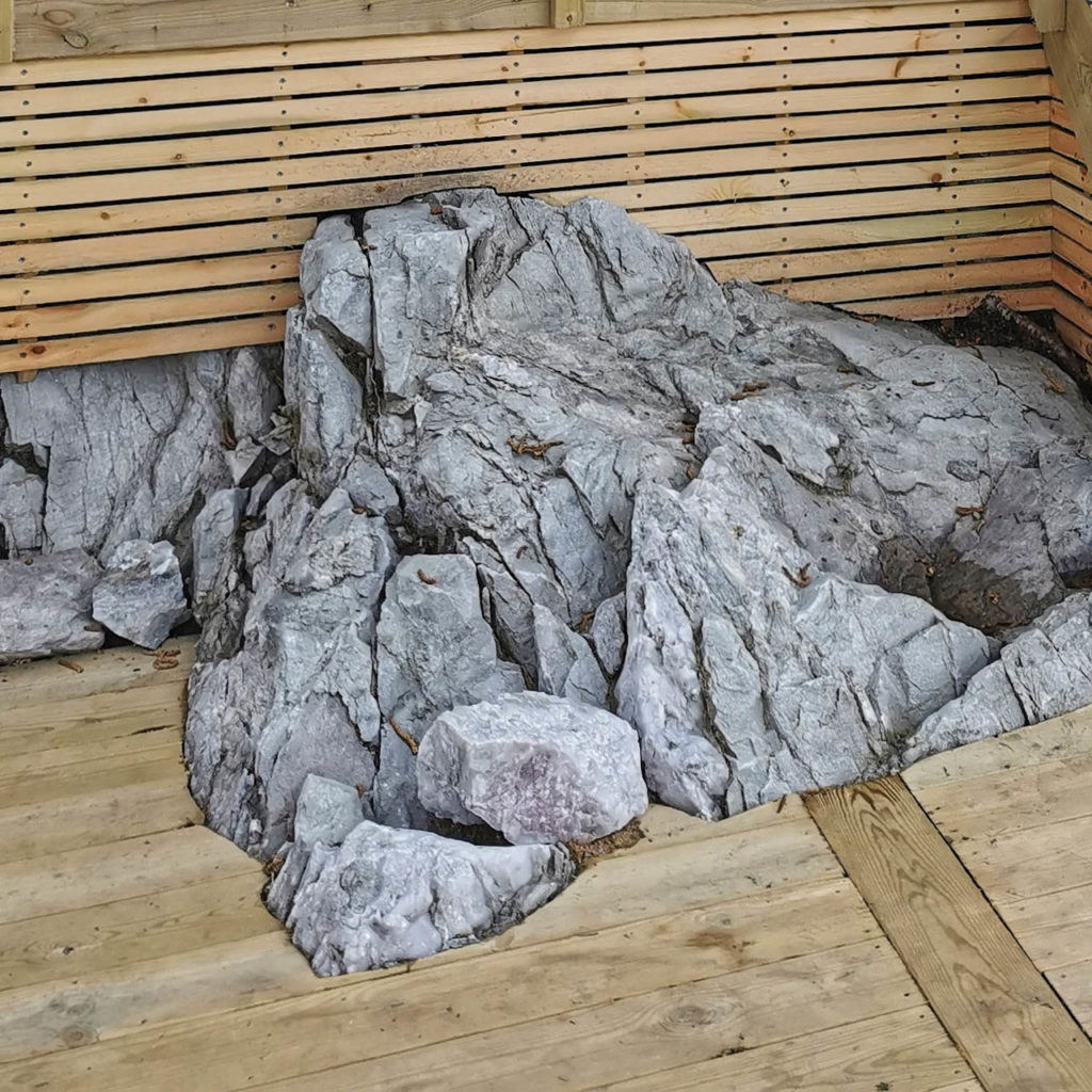 A detailed picture of how a wooden terrace is built against existing rocks and stones in the garden.