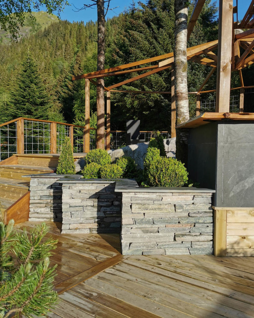 Three flower beds of slate drywall stand on a terrace. The flower boxes has a triangle shape. 
