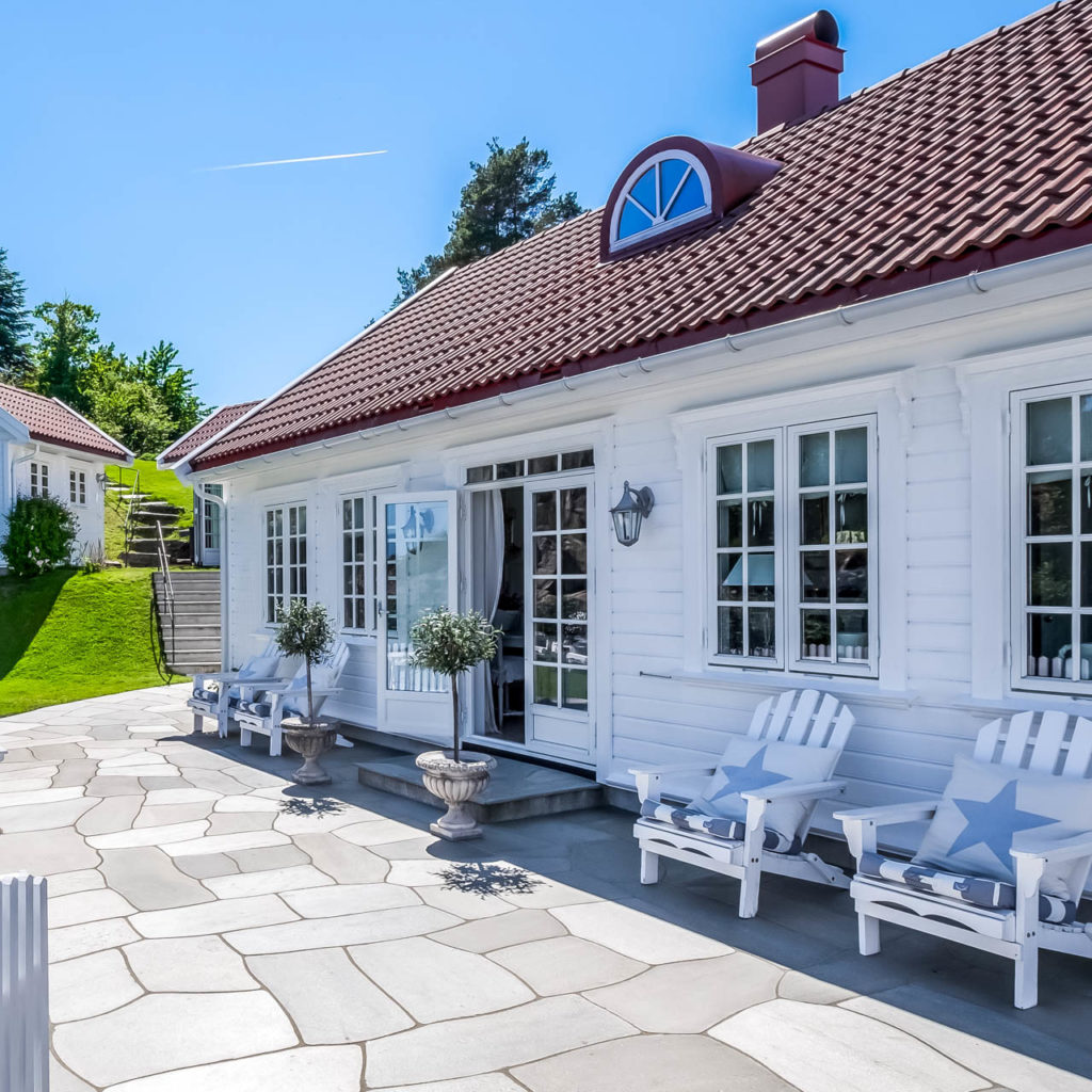 A patio with Oppdal slate crazy pavings and white wooden furniture.