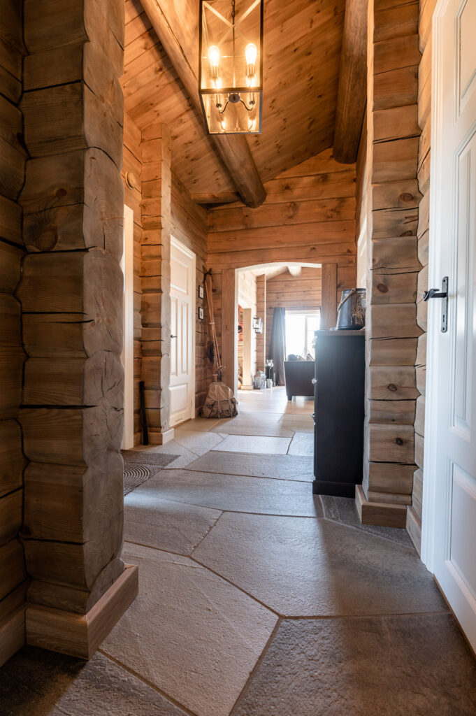 An entrance to a log cabin with large  crazy pavings on the floor