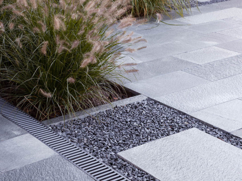 A detailed picture of slate outdoor tiles laid on a terrace and as a stepping stones directly on gravel.