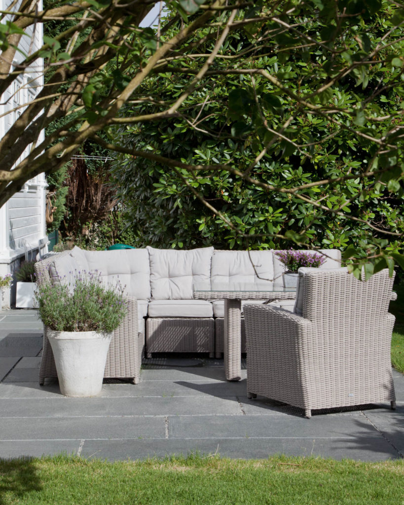 A patio under a tree with a sofa group on a cover of Offerdal slate.