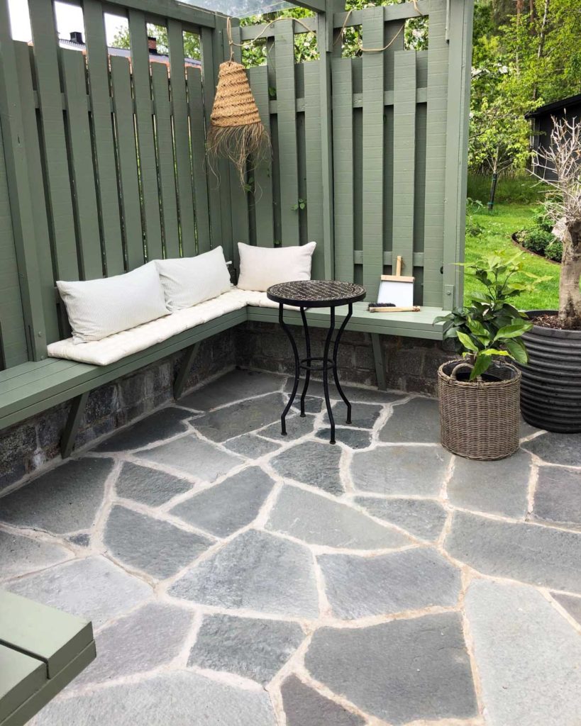 A terrace with slate crazy paving from Offerdal, Sweden  and green space-built wooden benches.