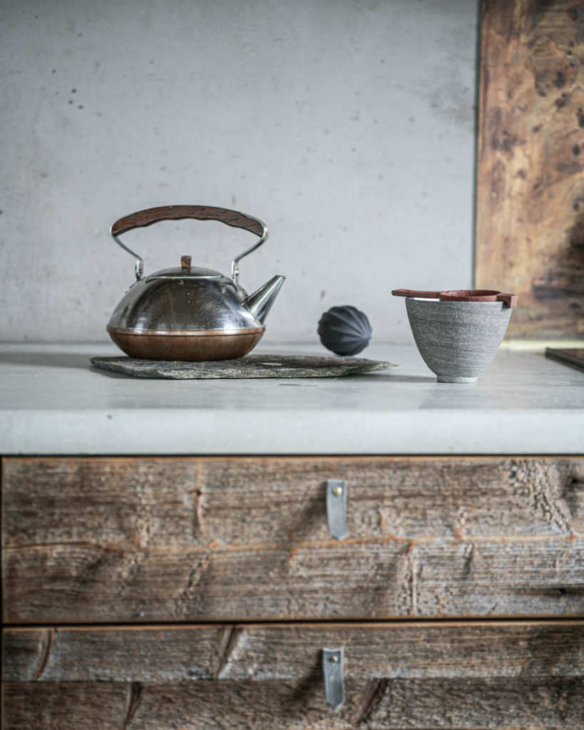 Et rustikt kjøkken hvor en skiferhelle benyttes som bordskåner for en kaffekanne.
