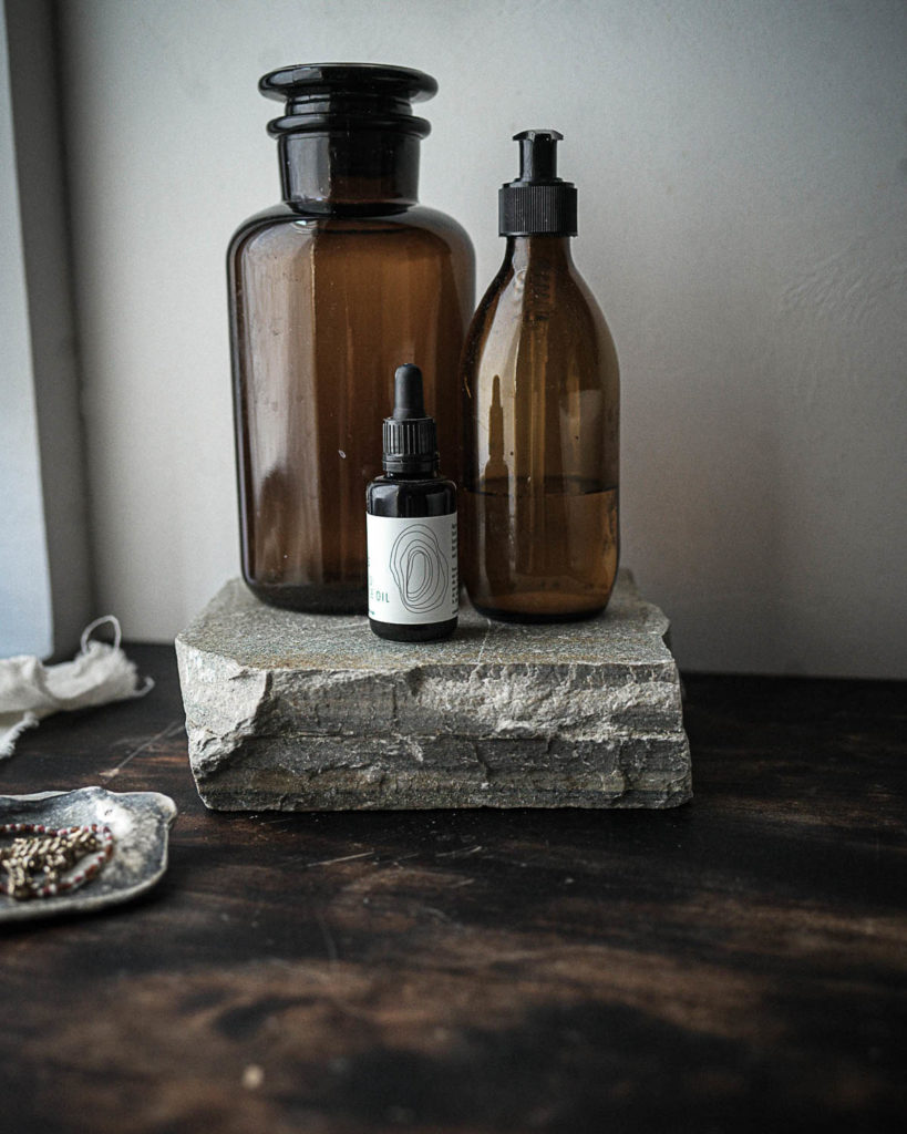 A bathroom with a dark wooden worktop and with a slate slab reused as a stand for hygiene items.