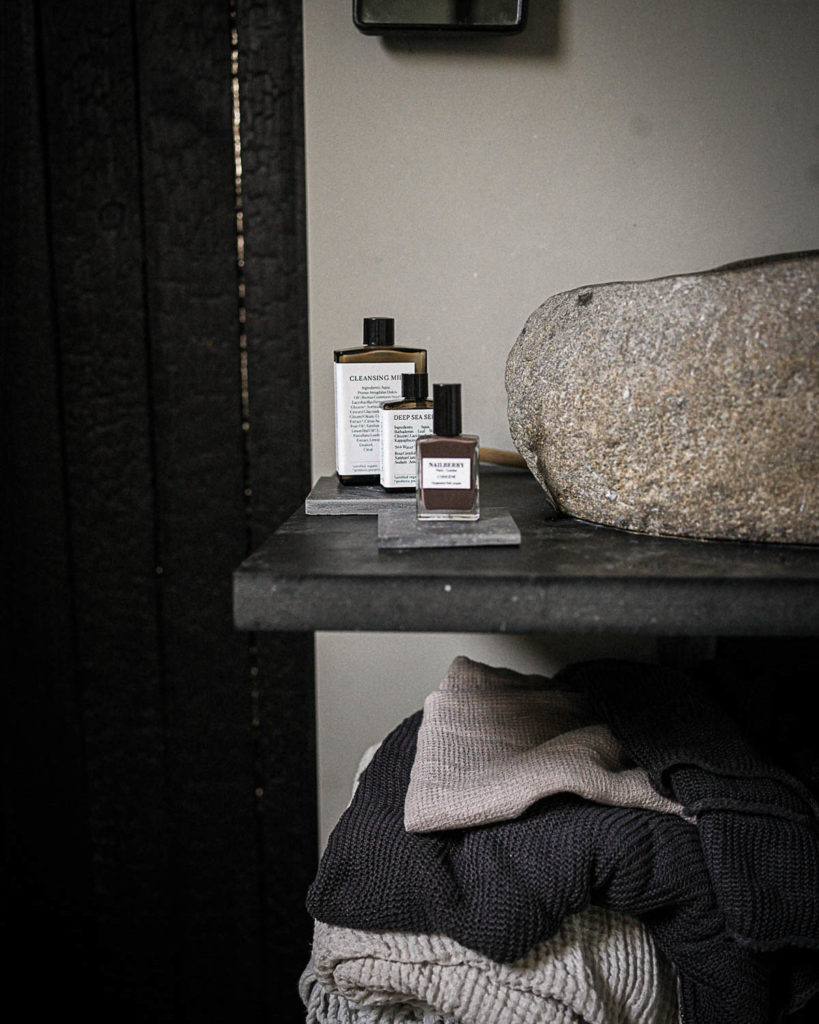 Ett badrum med stilrent handfat i sten och där skifferplattor används som bas för tvål och parfymer.