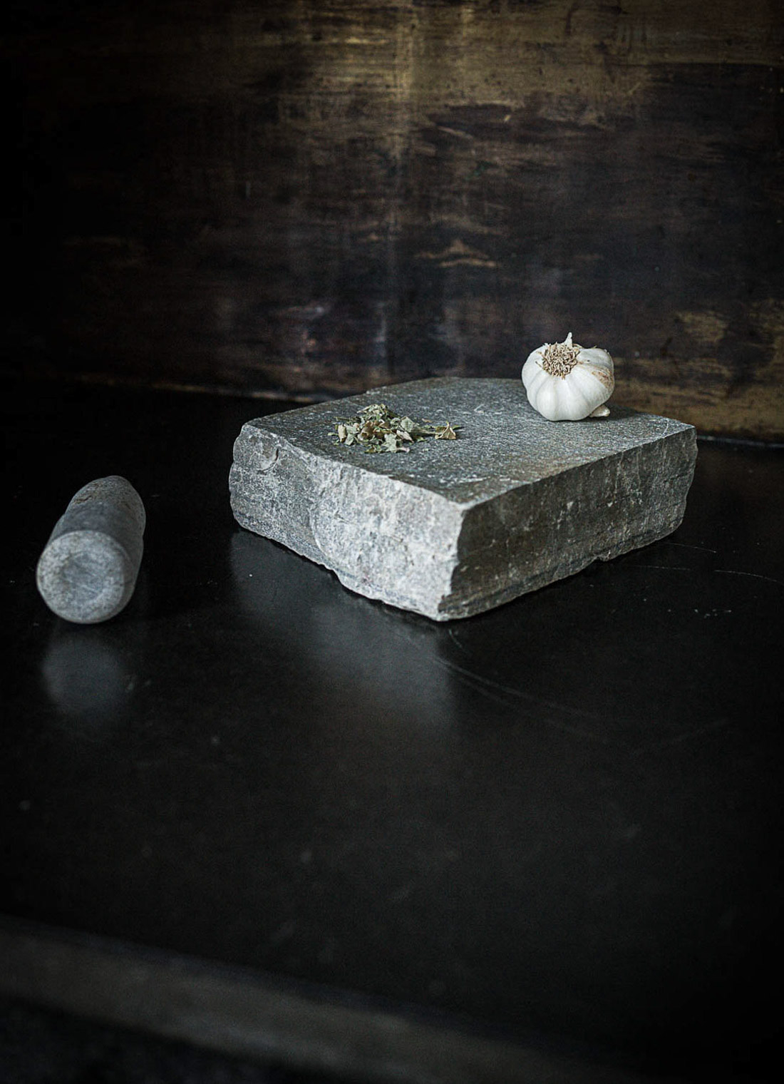 En skifer murstein i gjenbruk som morter. Oppå ligger hvitløk og krydder.