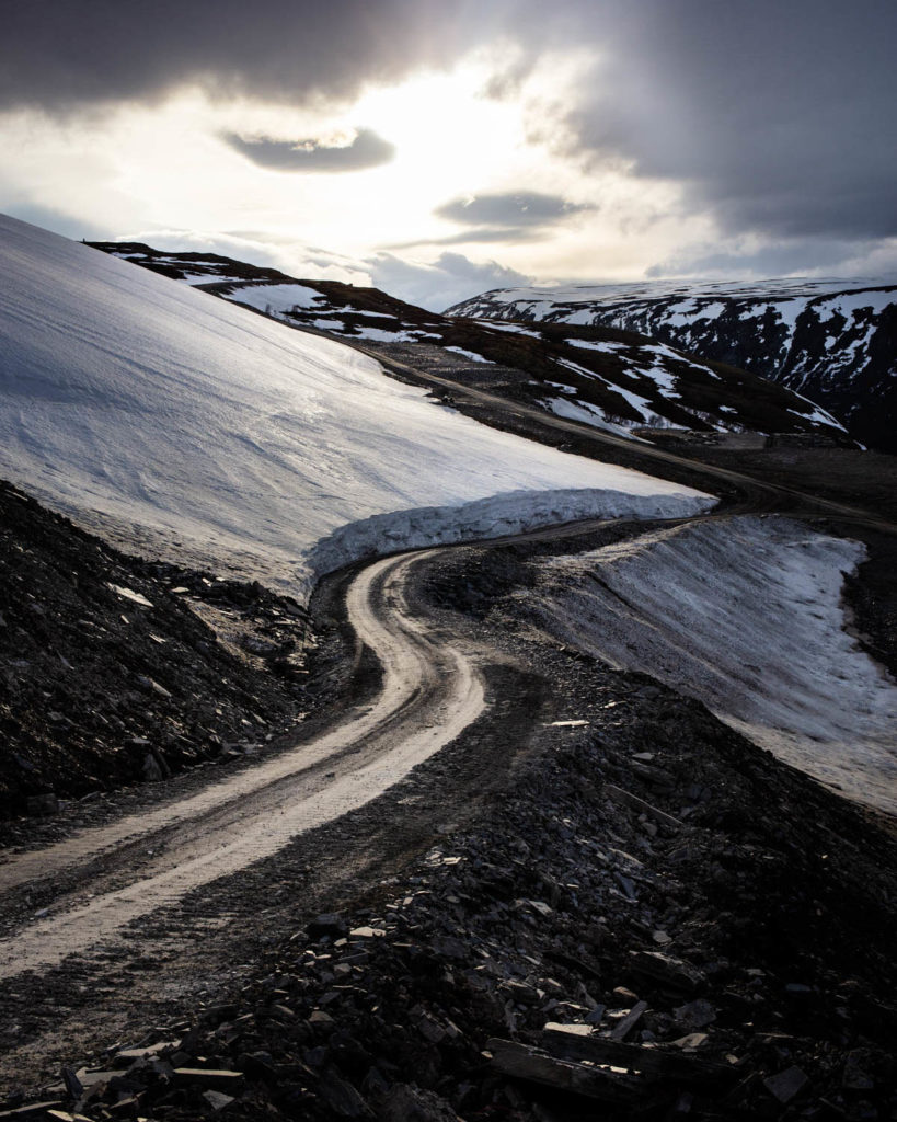A road that turns down from the slate quarry on  Sæterfjellet in Oppdal. The mountain is covered in snow.