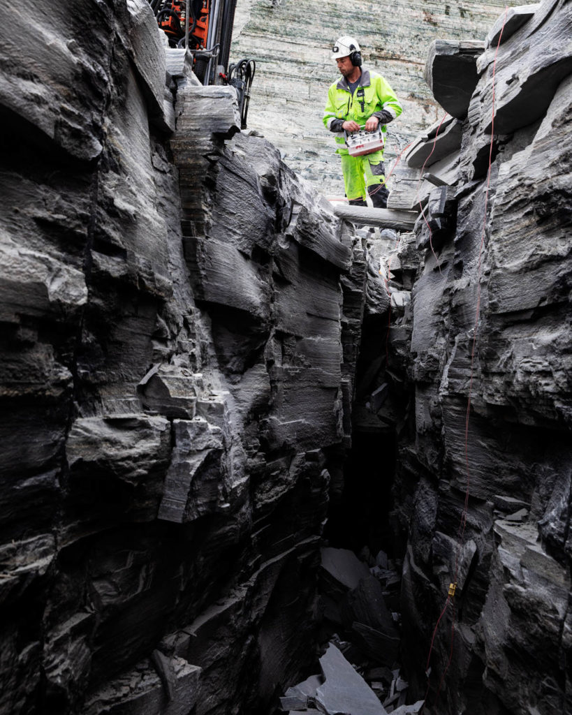 A blaster stands in a slate quarry in Oppdal, controlling the drilling rig with a remote control.