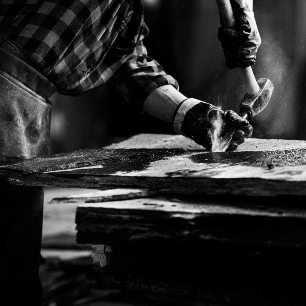 En stenhuggare på Minera Slate Offerdal som bearbetar Offerdalsskiffer med hammare och kilar