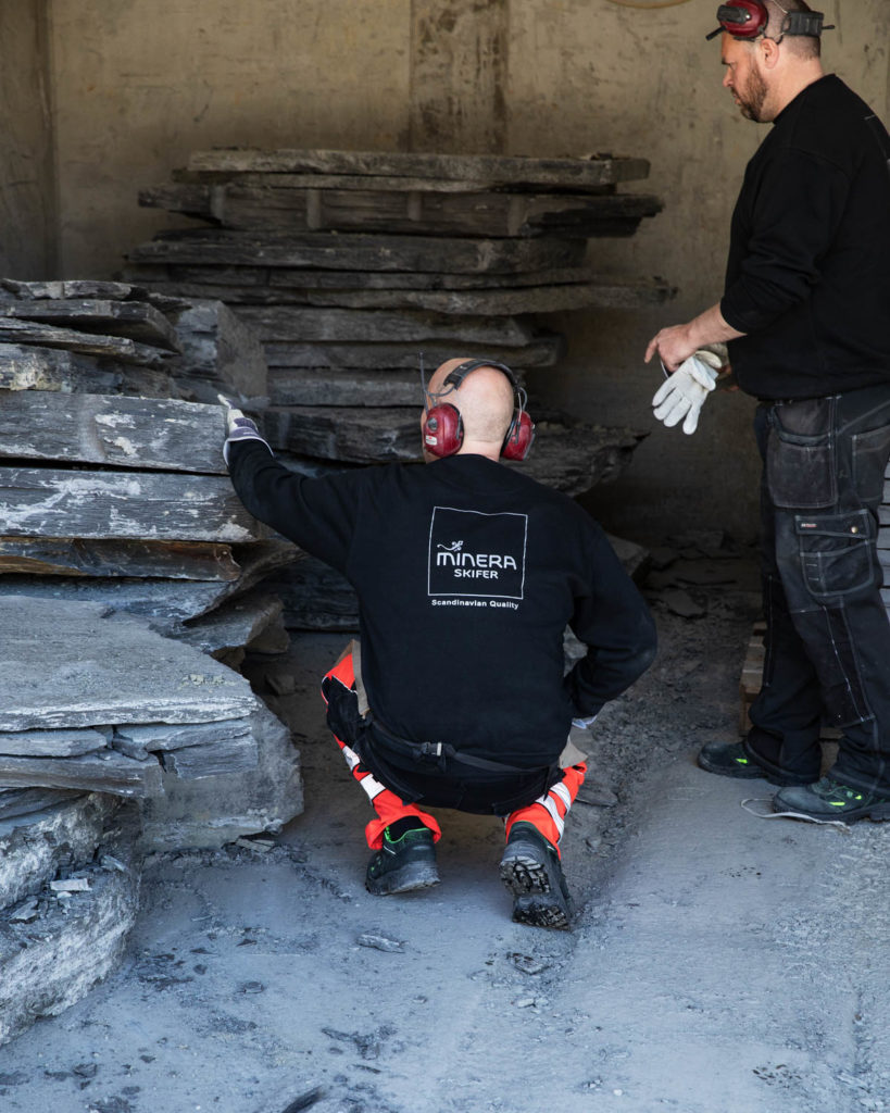 Two stonemasons are reviewing slate blocks of Otta Pillarguri slate inside the production hall.