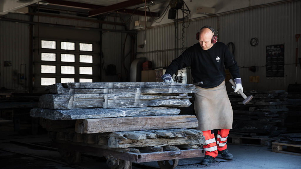 En steinhogger hos Minera Skifer kløver skiferplater av en stor blokk av  Otta Pillarguri skifer med hammer og mesisel