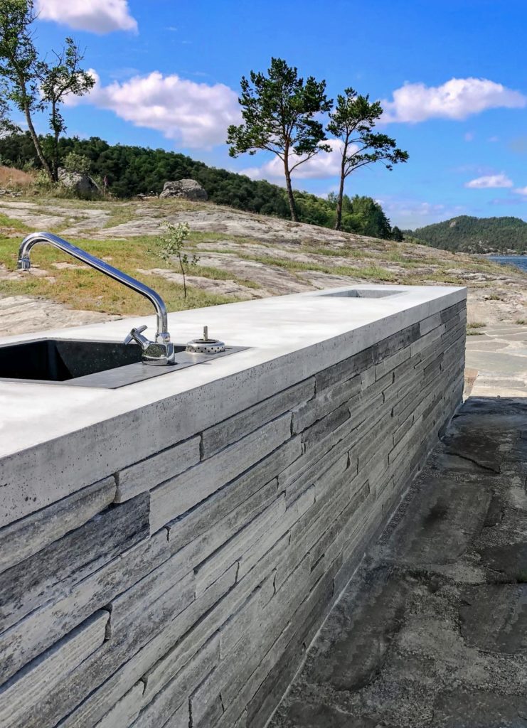 A long worktop of a slate outdoor kitchen located right by the sea. The base is made of Oppdal quartzite slate brick drywall.