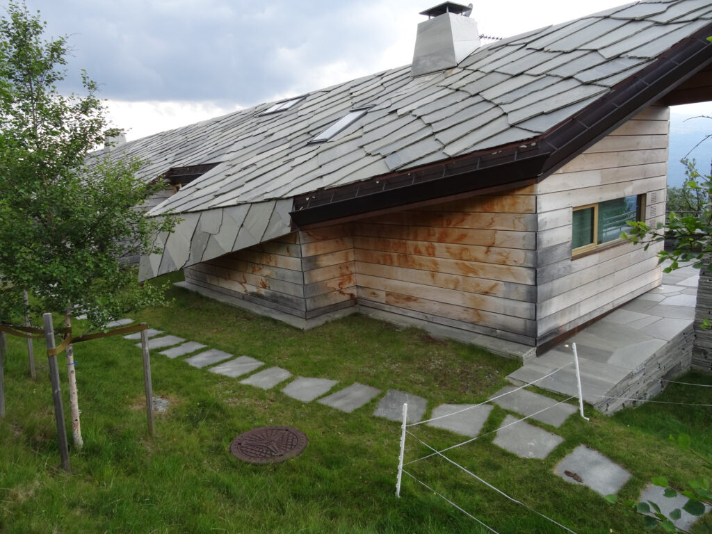 A modern cottage with a slate roof made of Oppdal quartzite flagstones and with stepping stones in a path on the lawn