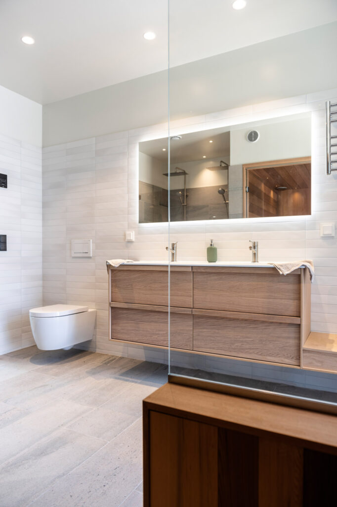 Ett badrum i naturmaterial som grått skifferkakel, ek och cederträ