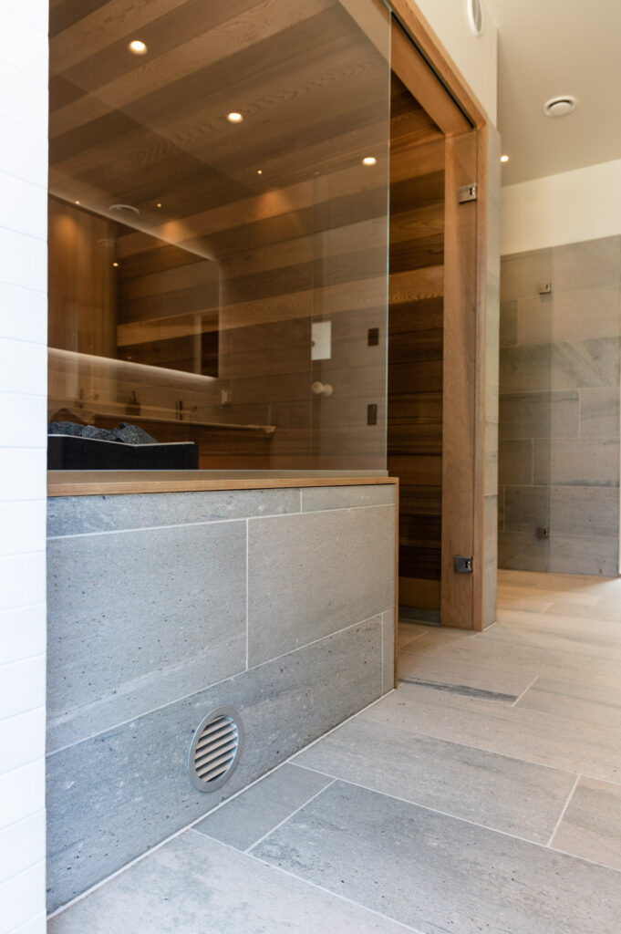 A bathroom with gray slate tiles on the floor and halfway up a sauna