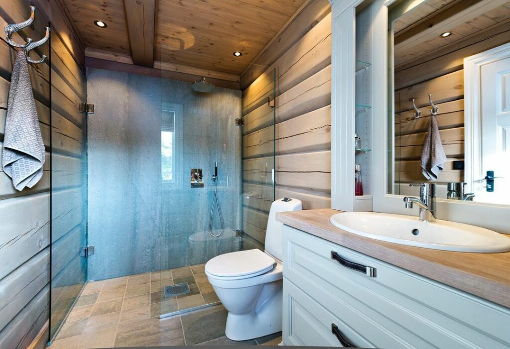 Ett badrum med en hel skifferskiva som duschvägg och gråa skifferklinker på golvet.